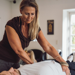 Underviser udfører kropsorienteret terapeutisk øvelse med kursist i trygge indendørs rammer – illustrerer nærvær, faglighed og den praktiske tilgang på Tobias‑Skolens psykoterapeutuddannelse, efteruddannelser og kurser.