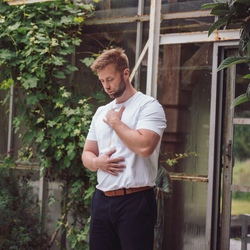 Person i mindful kropsøvelse med hænderne på bryst og mave i grønne, rolige omgivelser – illustrerer nærvær, selvkontakt og terapeutisk arbejde som på Tobias‑Skolens psykoterapeutuddannelse og efteruddannelser.