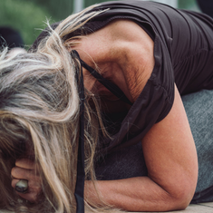 Person i en foroverbøjet kropslig position på en måtte under en øvelse på Tobias‑Skolen, med fokus på nærvær og kropsligt terapeutisk arbejde i naturlige omgivelser.