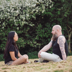 To personer sidder i græsset i rolige, grønne omgivelser og deltager i en nærværende samtale – illustrerer tryghed, relationel kontakt og personlig udvikling på Tobias‑Skolens psykoterapeutuddannelse, kurser og efteruddannelser.