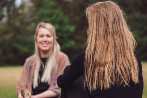 To personer på psykoterapeutuddannelse i nærværende samtale i grønne omgivelser – stemningsbillede der viser fordybelse, tryghed og relationel kontakt som en del af Tobias‑Skolens psykoterapeutuddannelse, kurser og efteruddannelser.
